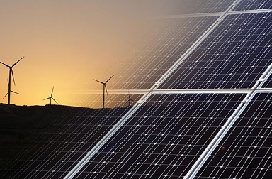 Solar panels in foreground with wind turbines in the backgrouund